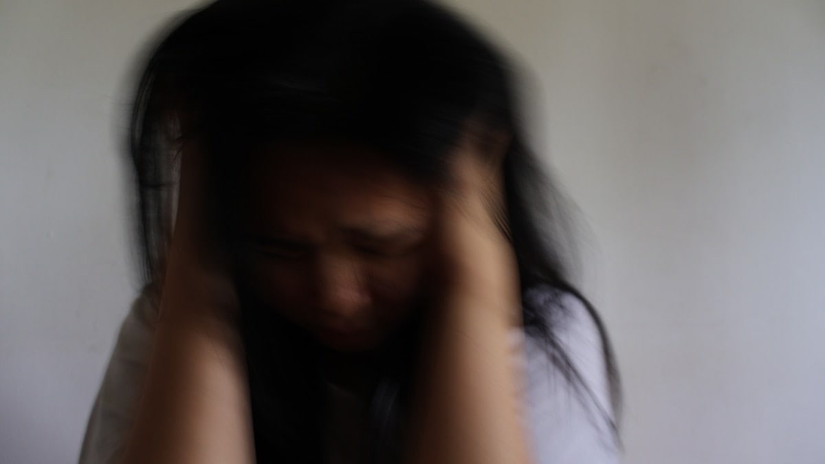 A blurred woman holding her head